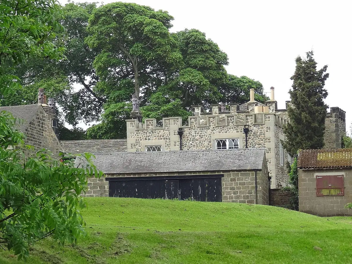 Cobble Hall, un bâtiment en pierre de style Tudor encadré par un grand arbre