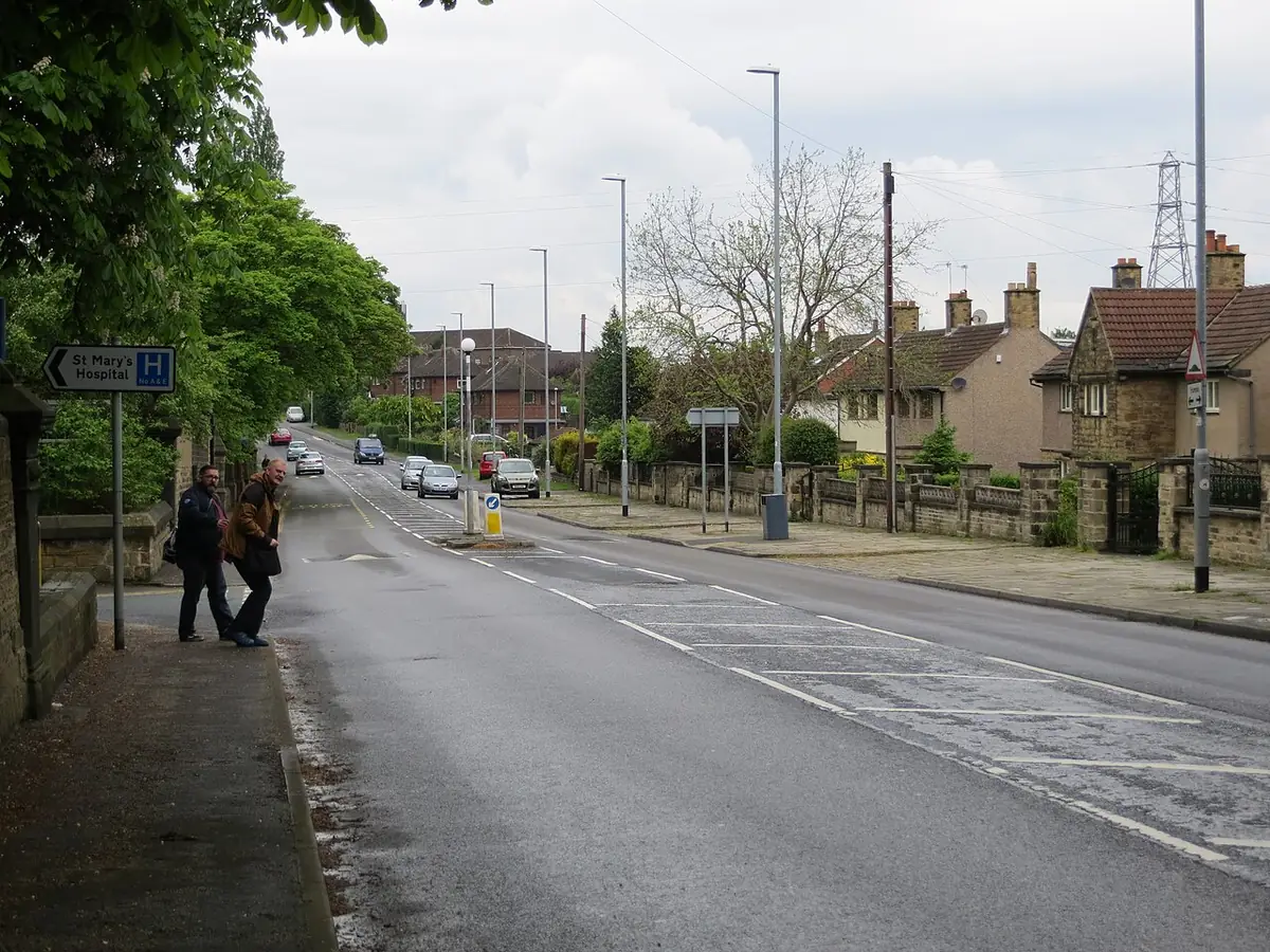 Une rue de Leeds bordée de maisons mitoyennes, des passants sur le trottoir