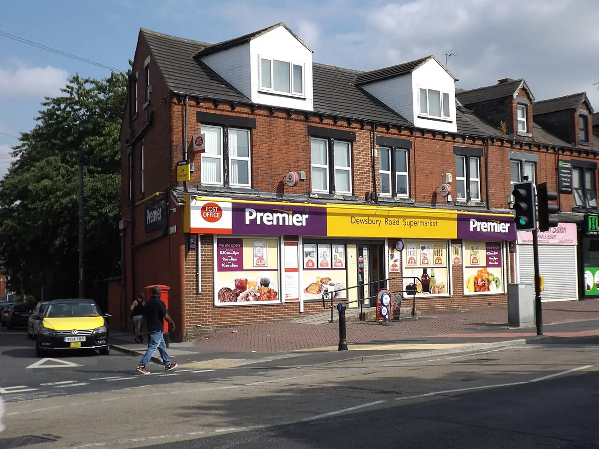 Un commerce d’angle avec des logements à l’étage, dans une rue de Leeds avec un passage piéton