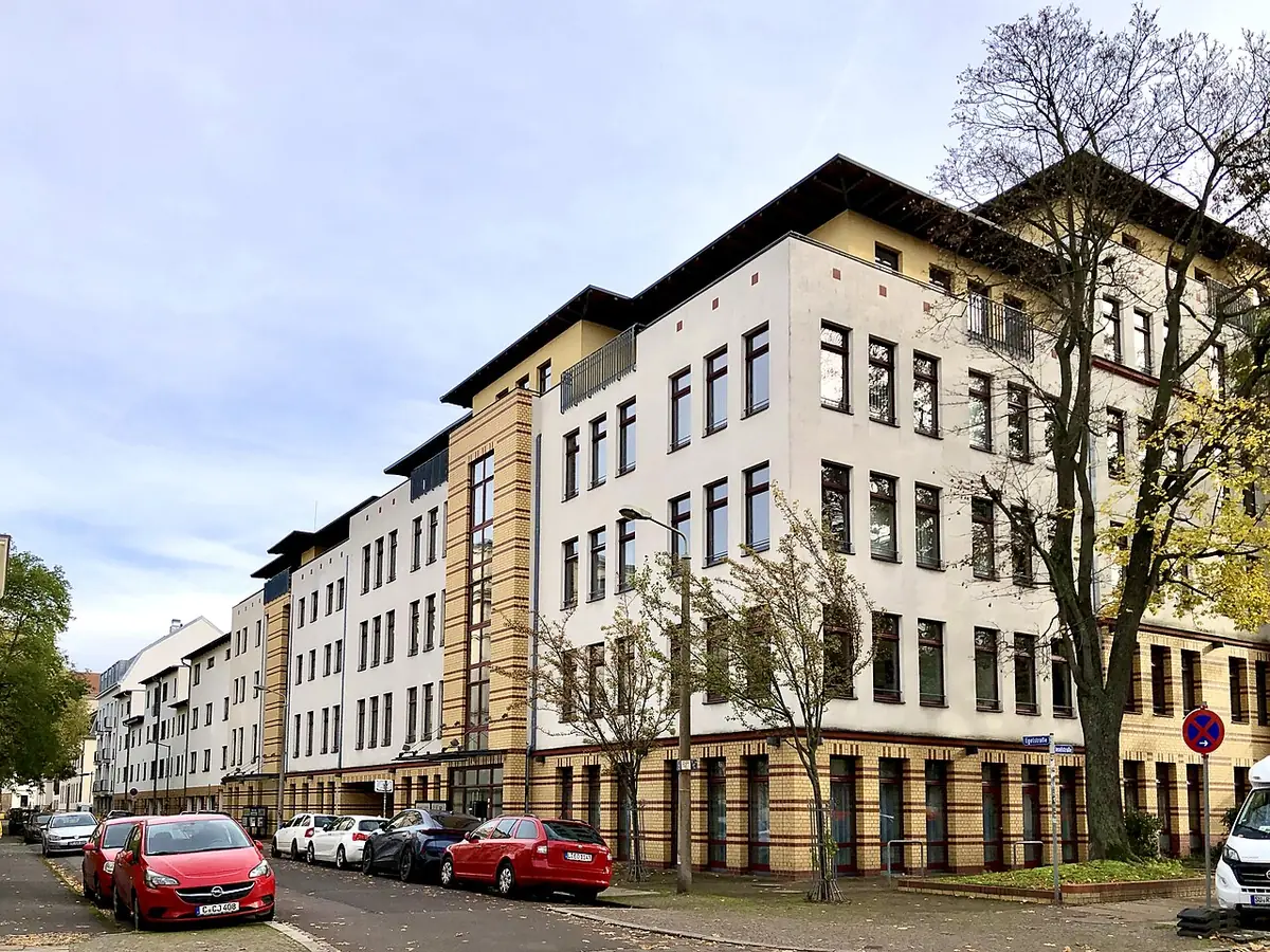 Un immeuble résidentiel blanc bordé de voitures garées à Leipzig