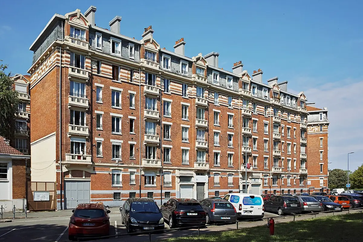 Un immeuble en briques rouges typique de Lille, voitures garées devant