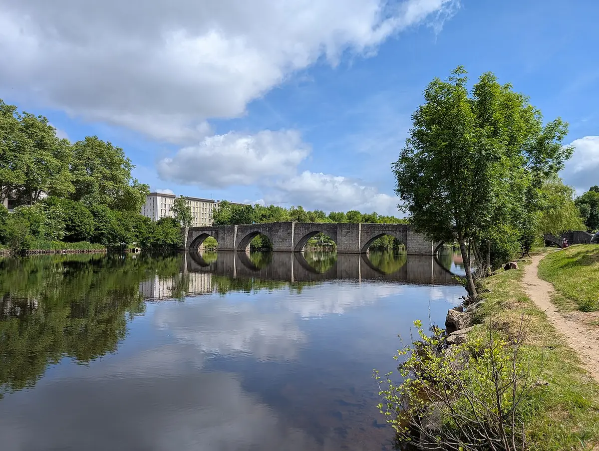 Le pont Saint-Étienne et ses arches en pierre sur la Vienne, berges arborées
