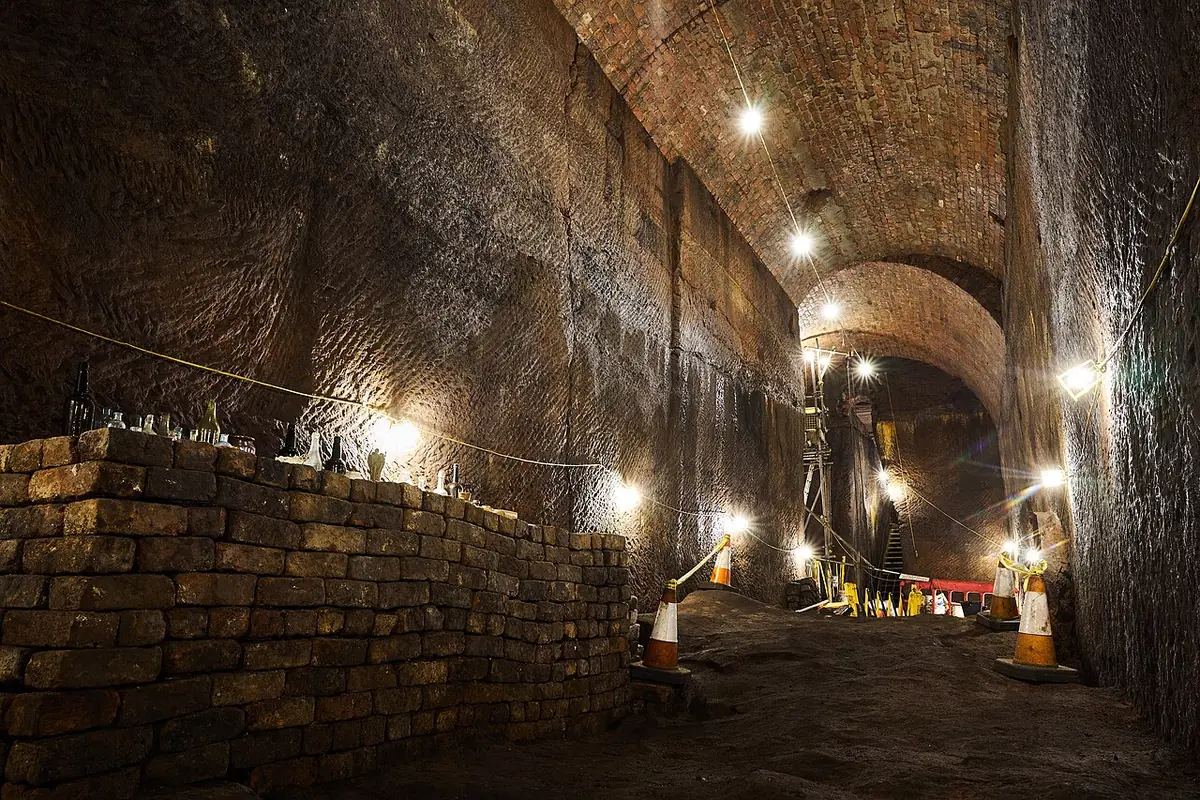 Un tunnel en brique éclairé, en cours de rénovation, avec barrières et cônes de sécurité