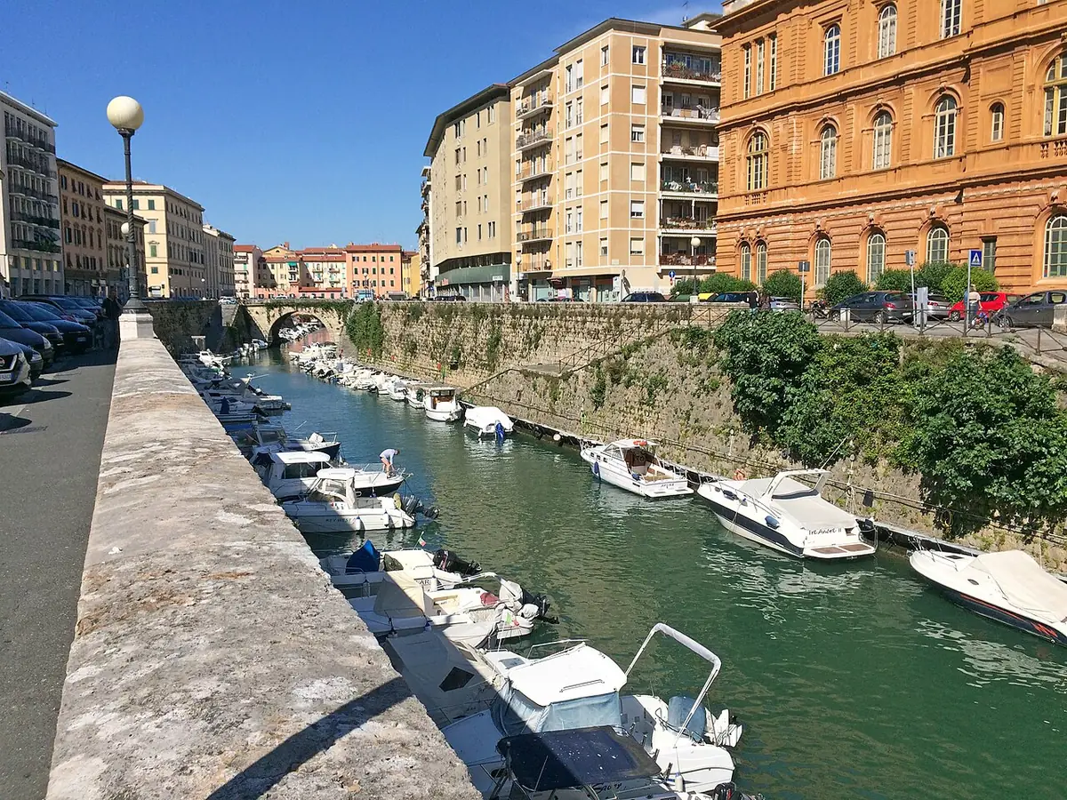 Canal de Livourne bordé de bateaux amarrés, d’un quai en pierre et d’immeubles ocre