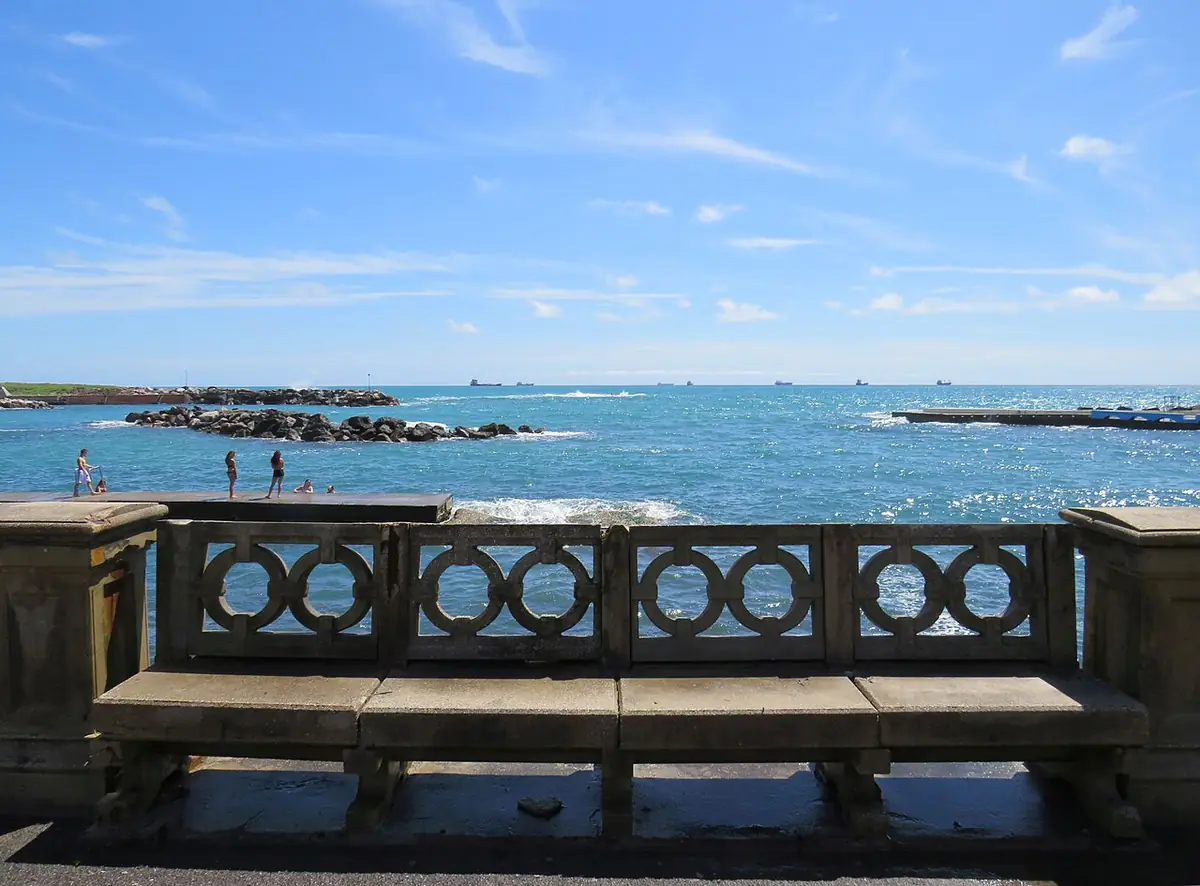 Banc en pierre intégré au parapet du front de mer de Livourne, mer bleue en face