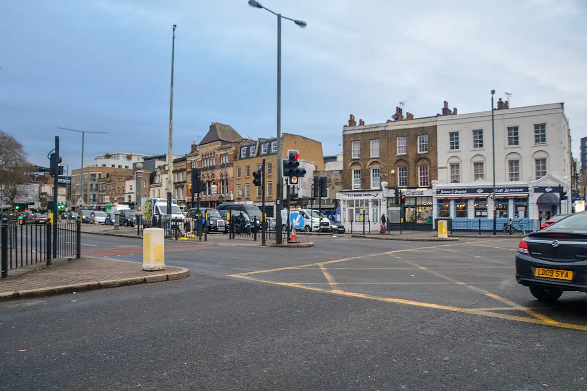 A busy London street junction lined with terraced houses and shops