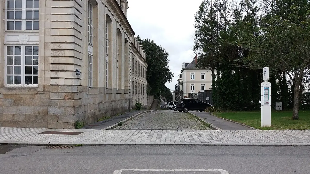 La rampe de l’Ancien Hôpital à Lorient, rue pavée entre un bâtiment en pierre et des arbres