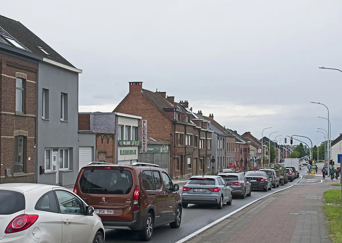 Une rue commerçante animée à Louvain, voitures et passants