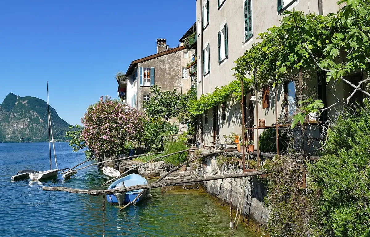 Un village au bord du lac de Lugano, bateaux amarrés devant les maisons