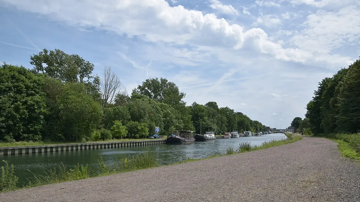 Un chemin le long d’un canal à Malines, une péniche au loin
