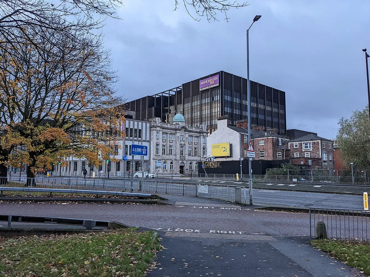 Un bâtiment moderne aux panneaux noirs à côté de bâtiments en pierre plus anciens à Manchester