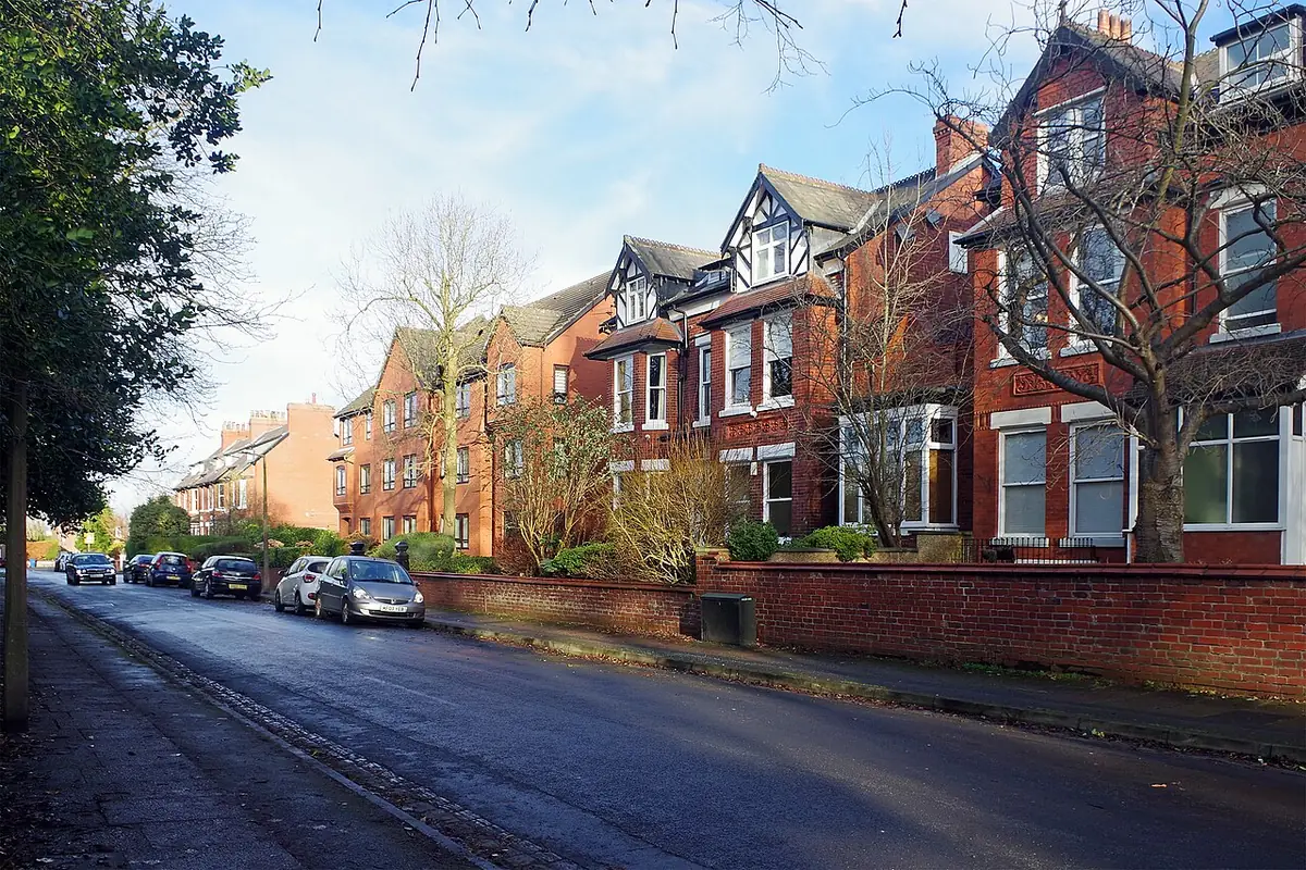 Une rue de maisons mitoyennes en brique rouge avec bow-windows et voitures garées