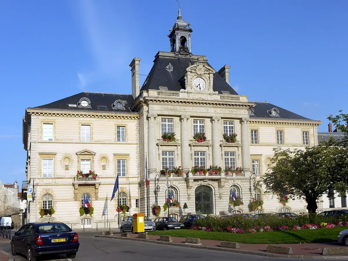 L’hôtel de ville de Meaux, façade à campanile et parterres fleuris sous un ciel bleu