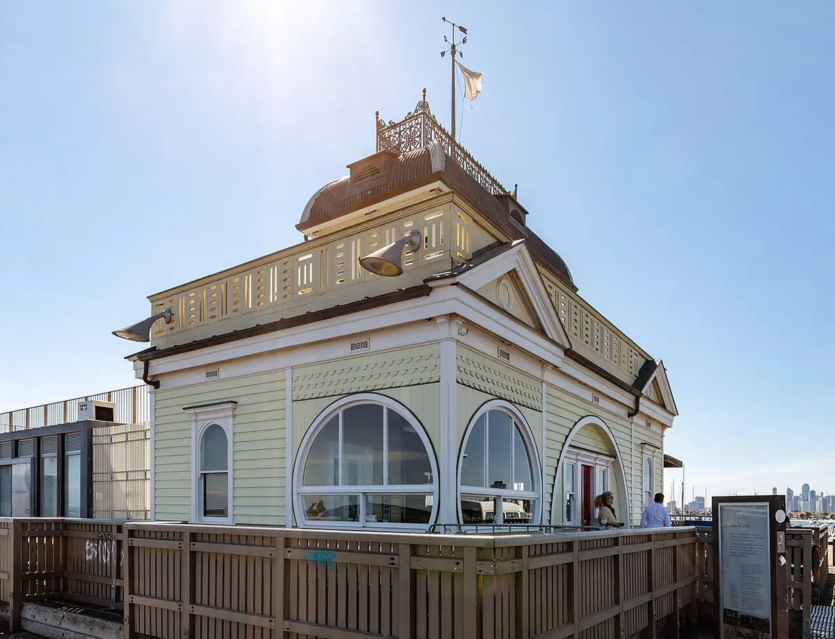 Le pavillon de la jetée de St Kilda, bâtiment crème et vert aux fenêtres cintrées, sous un ciel bleu