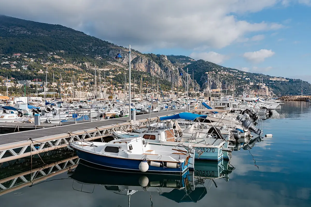 Bateaux amarrés au port de Menton, eau calme et montagnes en arrière-plan