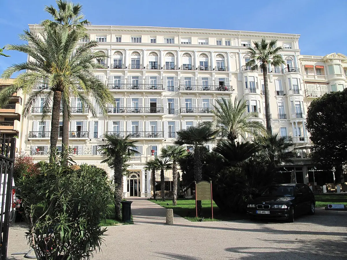 Façade blanche de l’hôtel Royal-Westminster à Menton, avec palmiers et balcons