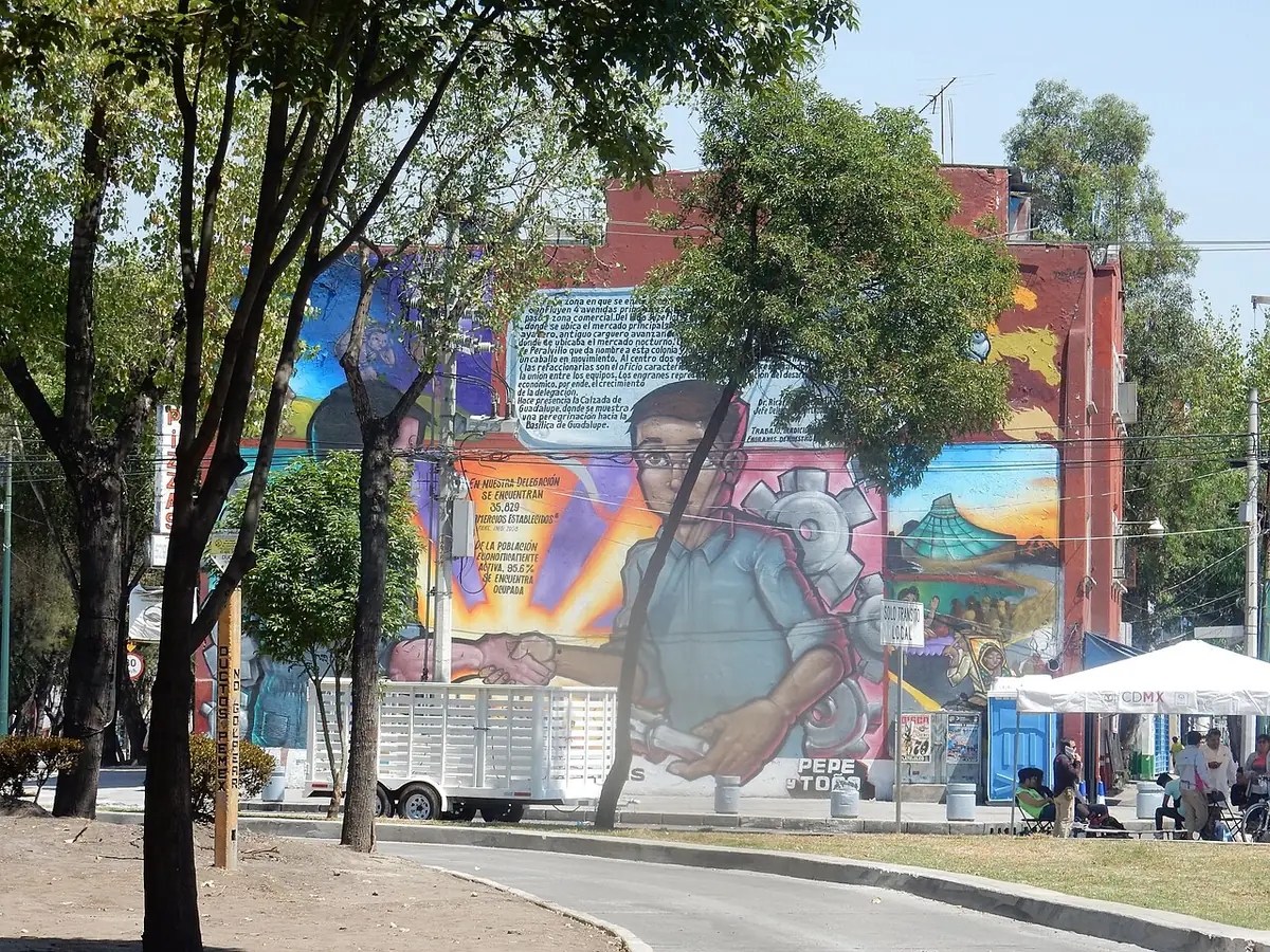 Rue arborée de Mexico, grande fresque murale sur un immeuble en brique