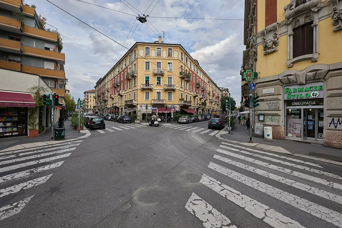 Via Antonio Stoppani à Milan, carrefour avec passages piétons et immeubles anciens colorés