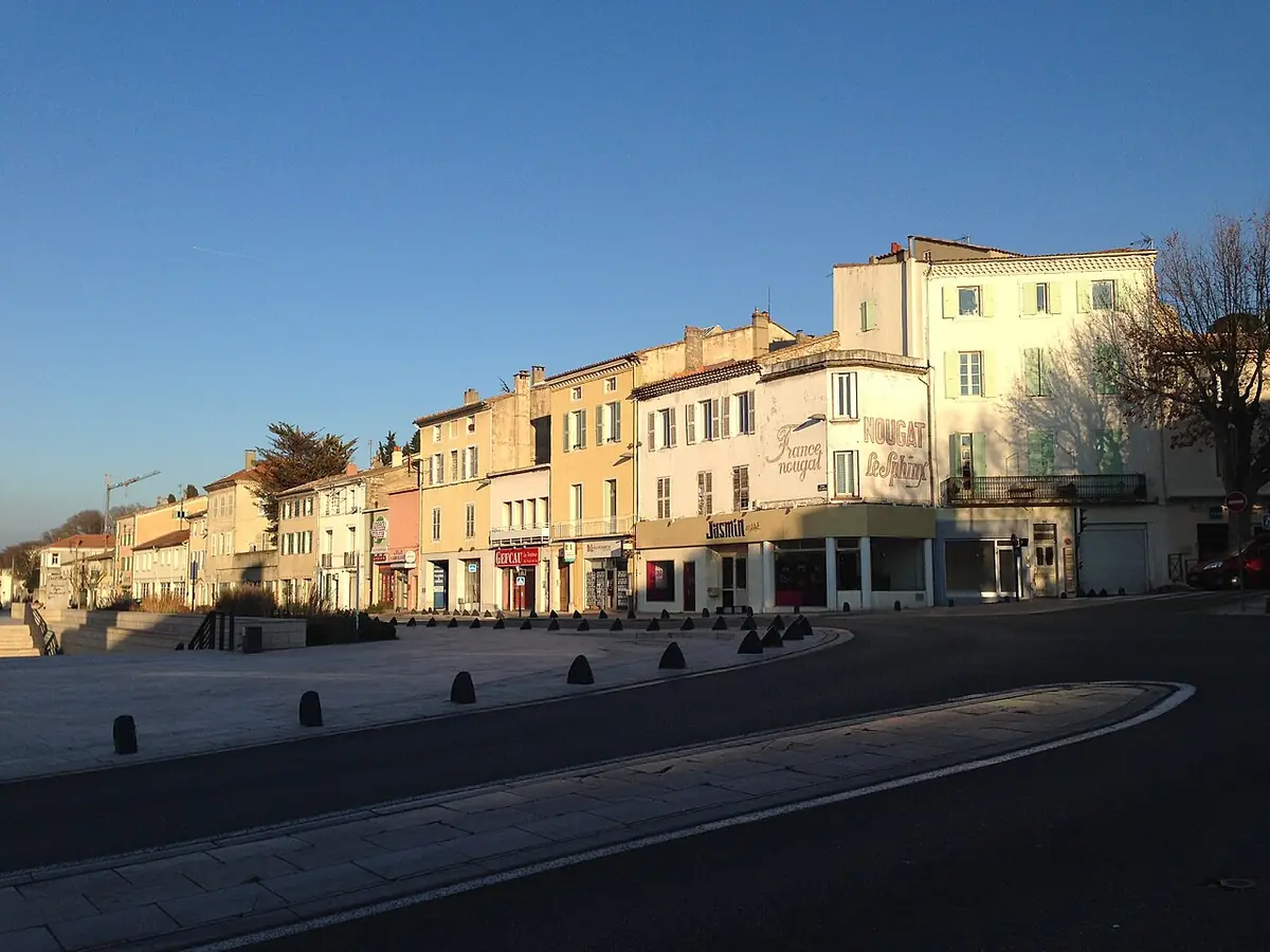 Rangée de façades colorées le long d’une large rue de Montélimar, éclairées par un soleil rasant