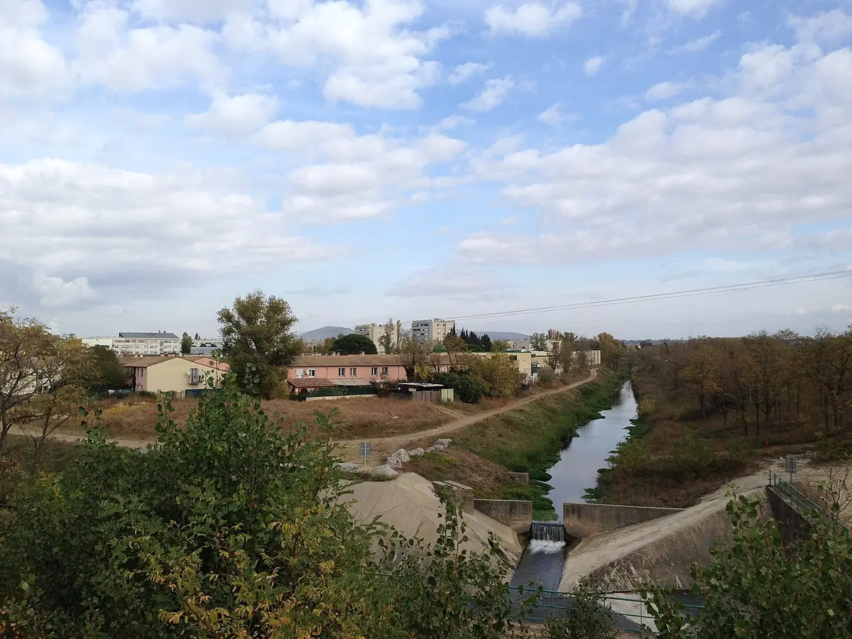 Vue vers le quartier Pracomtal de Montélimar, maisons et petit cours d’eau entre les arbres