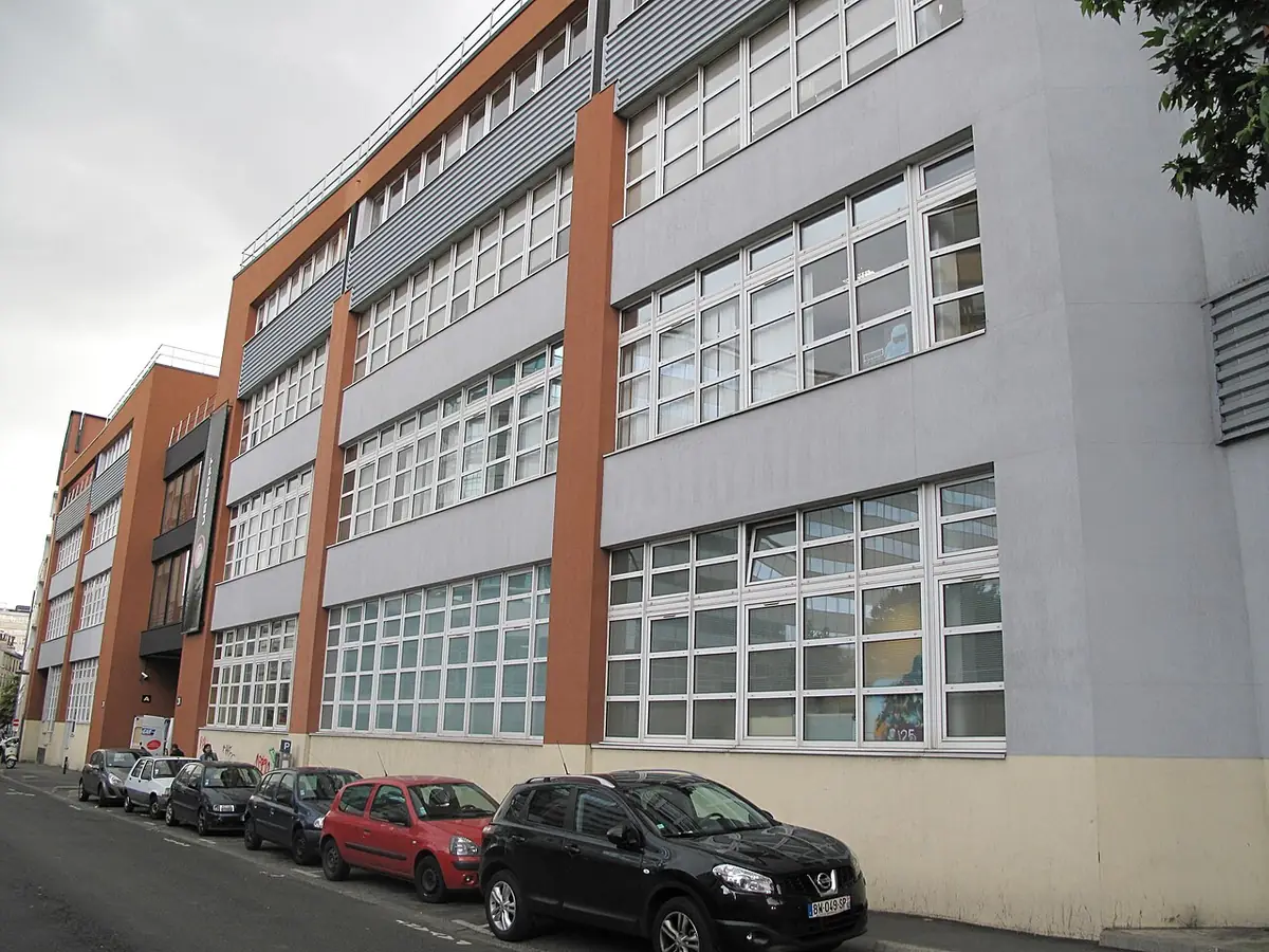 Grand bâtiment en brique et bardage gris, voitures garées rue Armand-Carrel à Montreuil