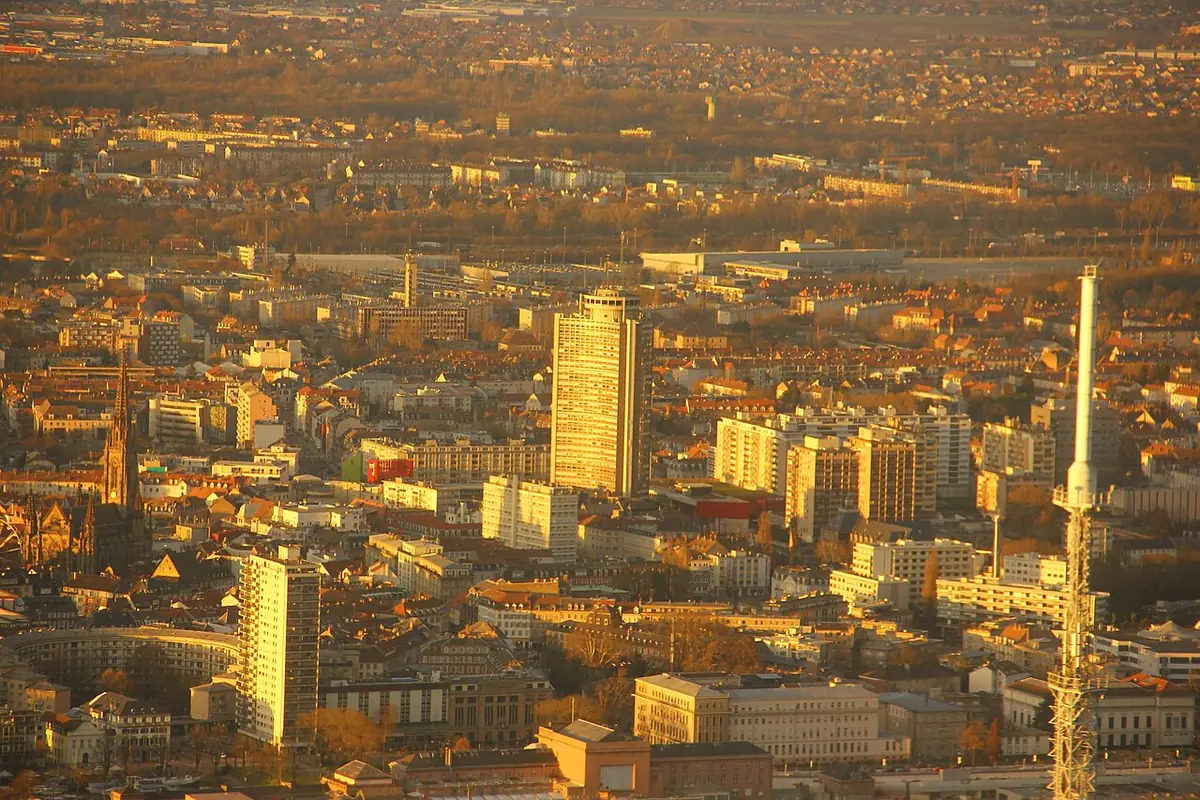 Vue en hauteur sur Mulhouse baignée de lumière dorée, avec la tour de l’Europe et les toits de la ville