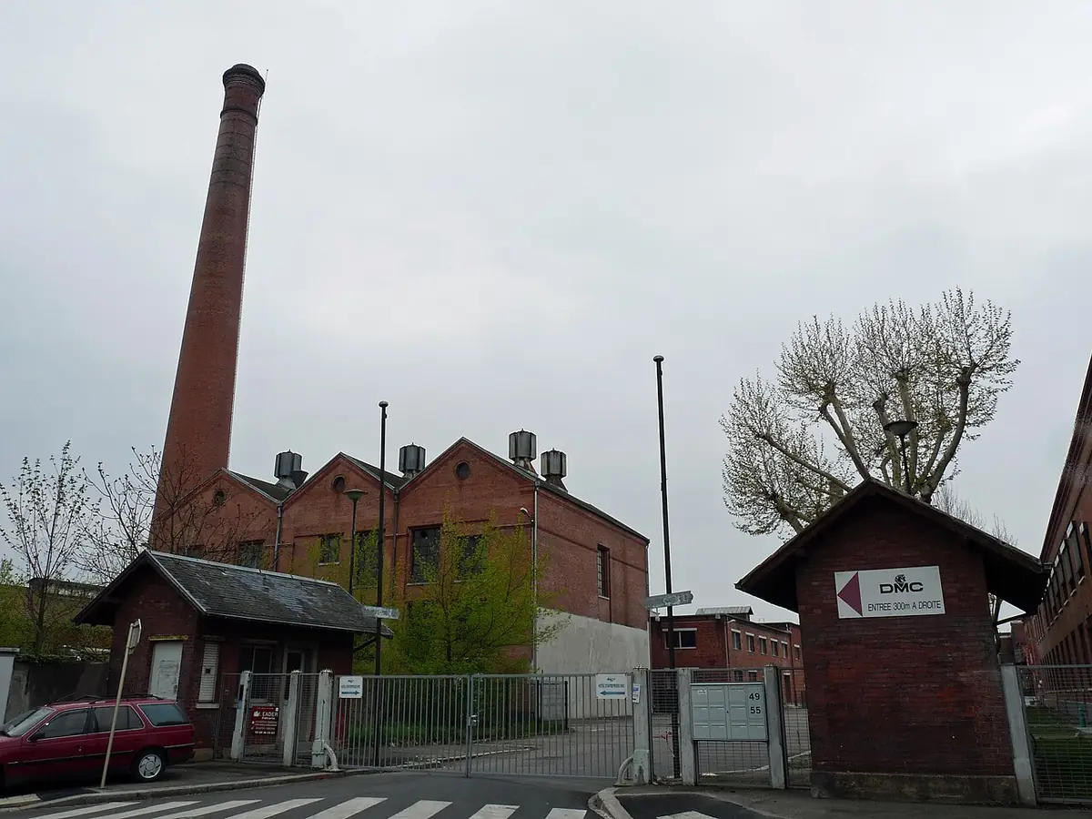 Anciens bâtiments en brique et haute cheminée d’usine sur le site DMC à Mulhouse