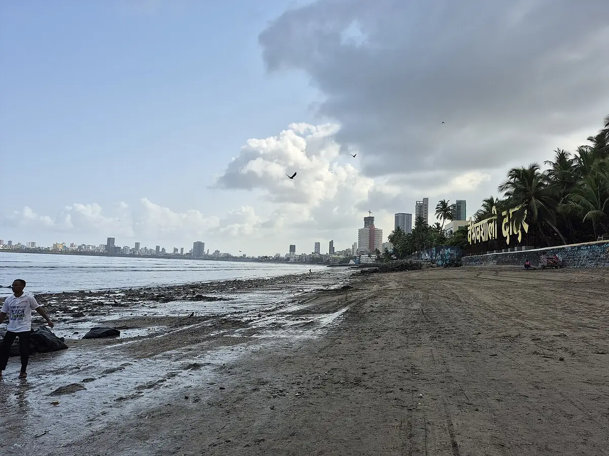 La plage de Dadar Chowpatty à Bombay à marée basse, palmiers et tours le long du rivage