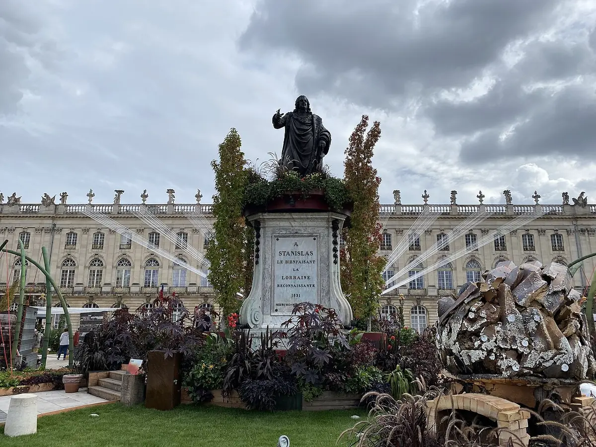 La place Stanislas à Nancy, statue au centre entourée d’un jardin éphémère, façades classiques au fond