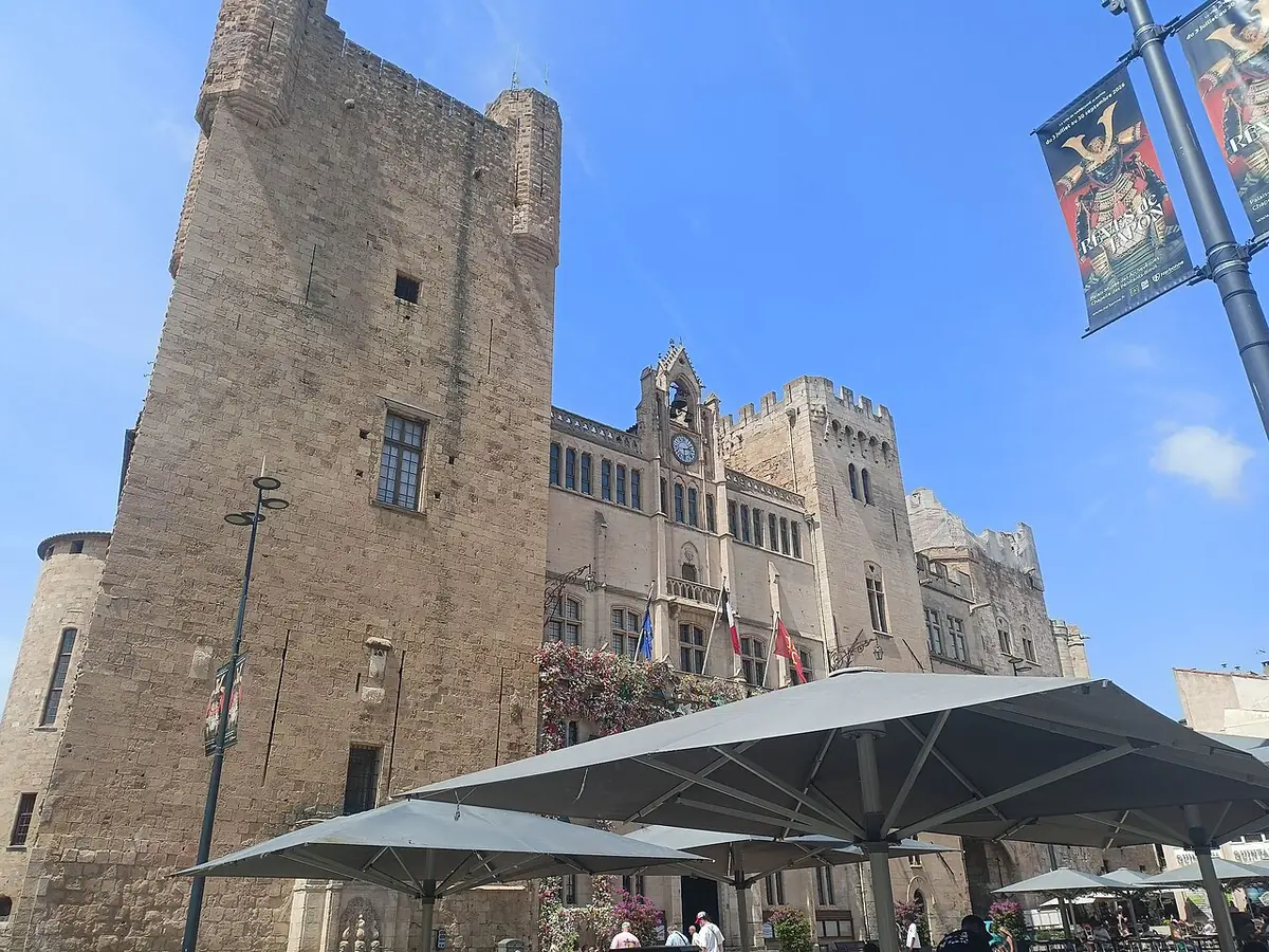 Place de l’Hôtel-de-Ville à Narbonne, tour médiévale et palais des Archevêques, parasols en terrasse