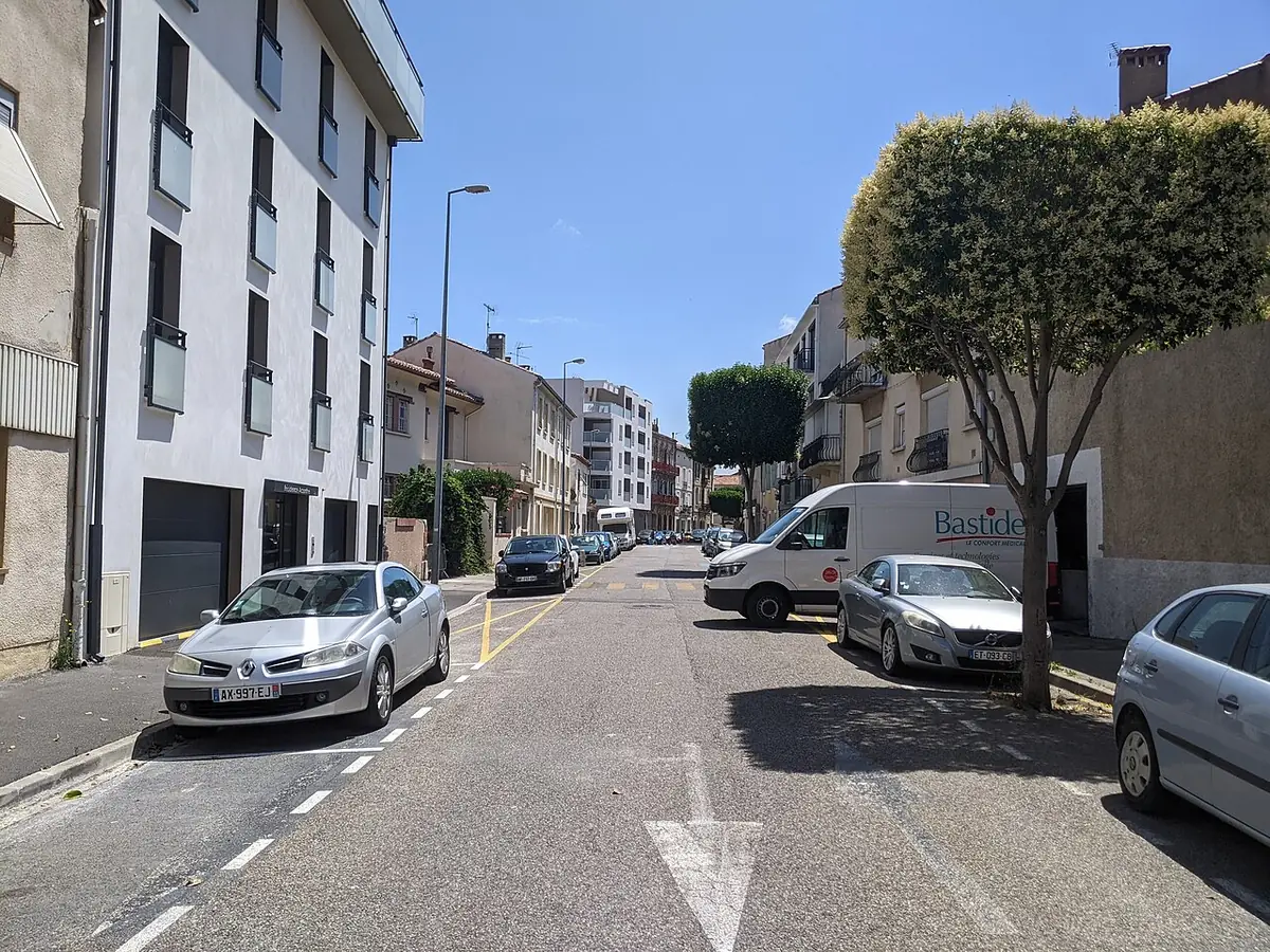 La rue Chanzy à Narbonne, immeubles récents et maisons, voitures garées le long de la rue