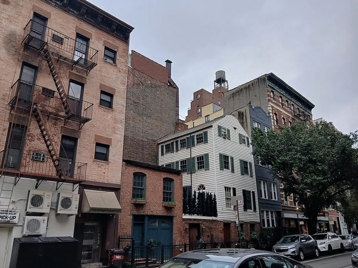 Des immeubles en brique avec escaliers de secours en fer le long d’une rue étroite