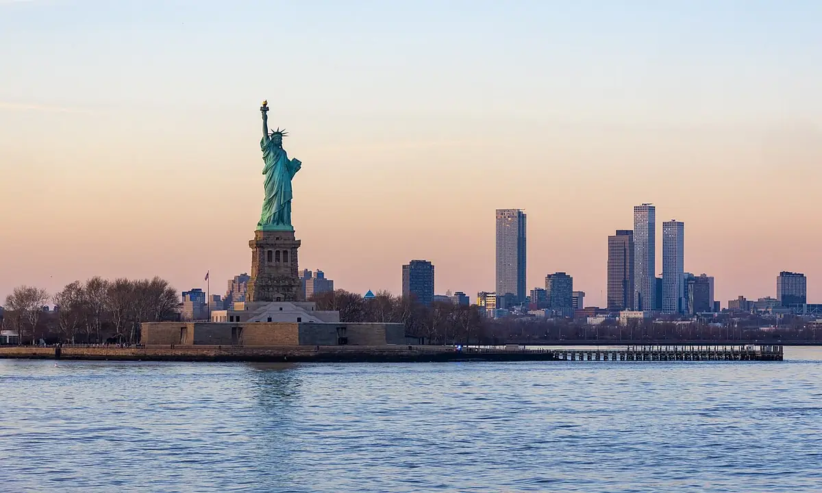 La statue de la Liberté en silhouette au coucher du soleil, la ligne d’horizon de Manhattan derrière
