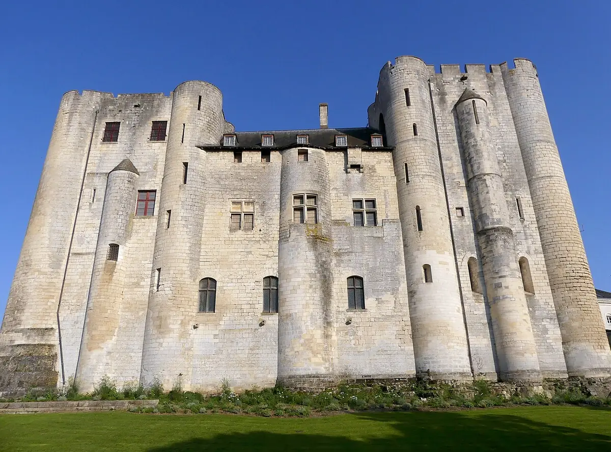 Le donjon de Niort, ses tours rondes en pierre sous un ciel bleu