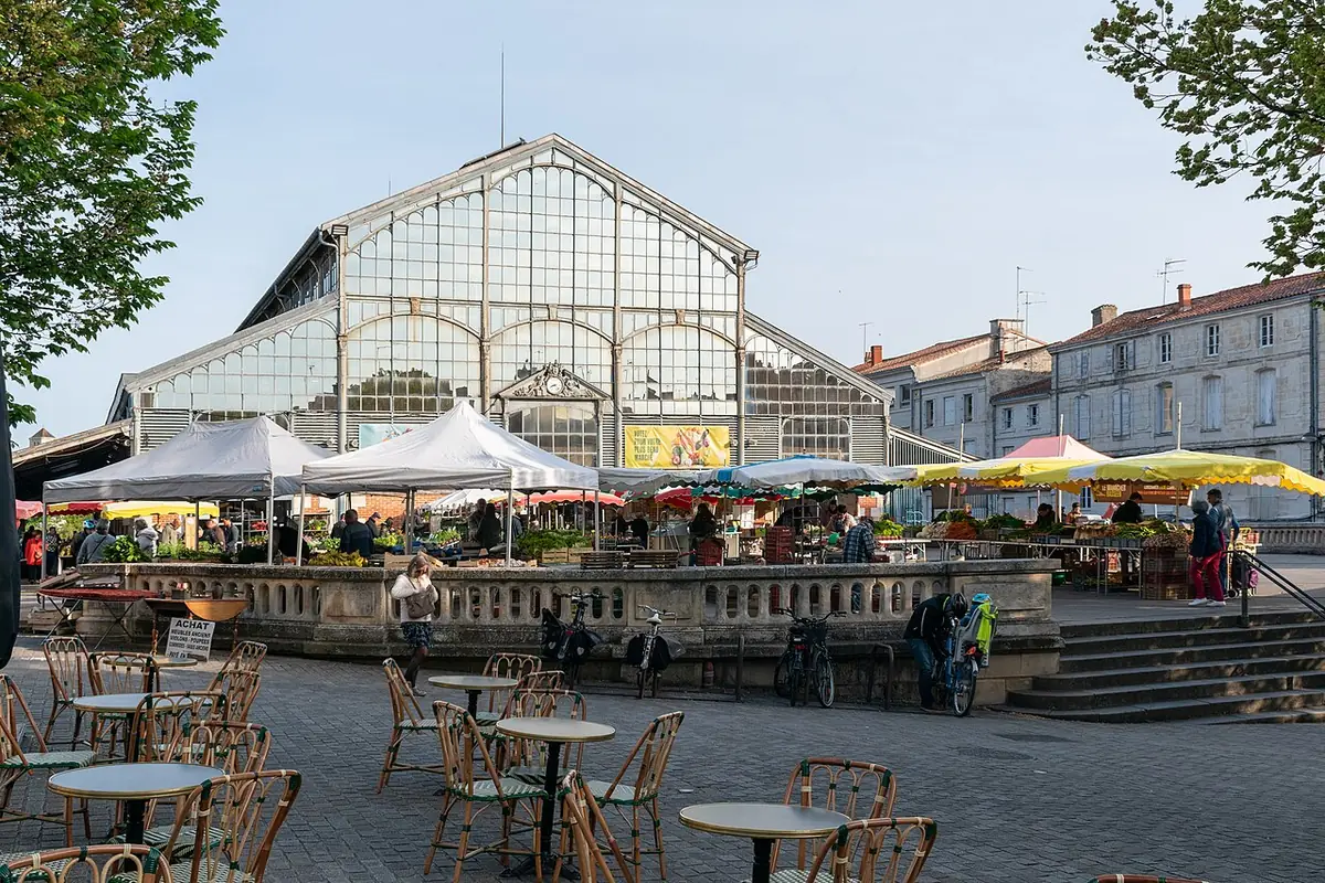 Étals du marché devant les halles de Niort et leur grande verrière, terrasse de café au premier plan