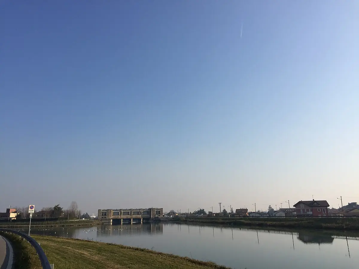Le canal Scaricatore à Padoue, eau calme et berges herbeuses sous un ciel clair