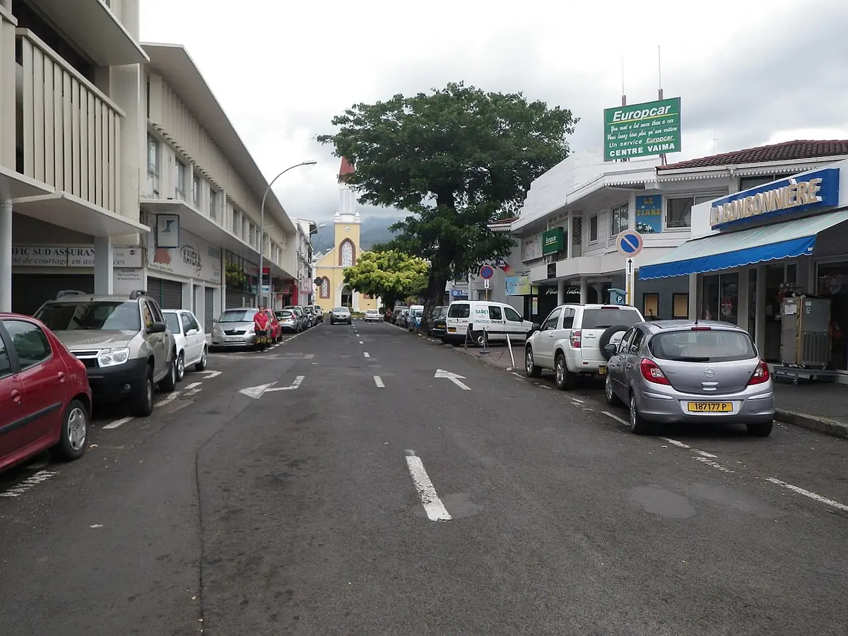 Une rue du centre de Papeete bordée de commerces, la cathédrale Notre-Dame au bout