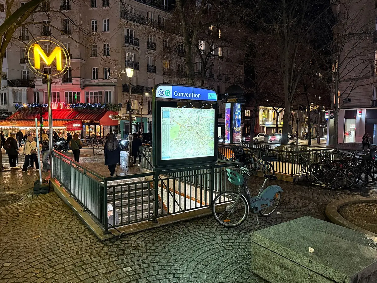 L’entrée de la station Convention illuminée le soir, vélo garé à proximité