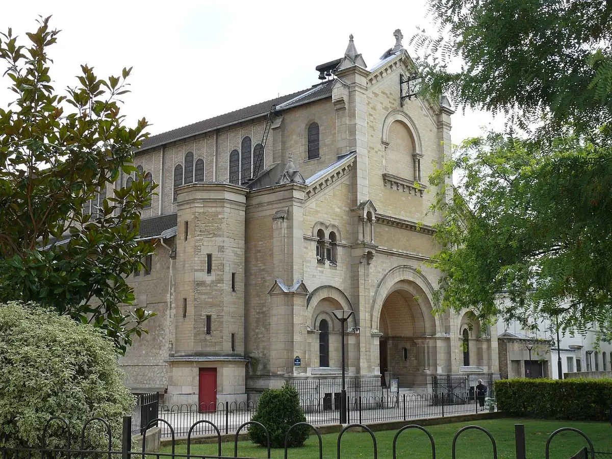 L’église Notre-Dame-du-Travail, façade en pierre entourée d’arbres