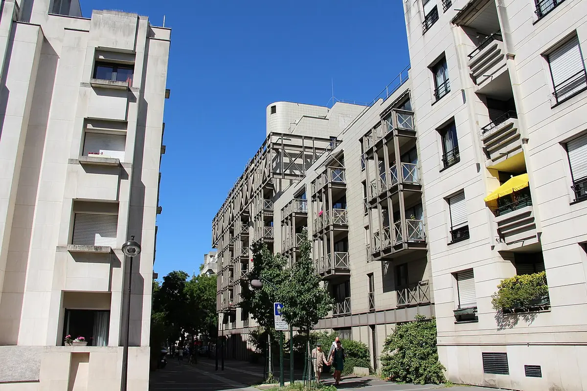 Un immeuble résidentiel avec balcons, vu depuis la rue, ciel bleu