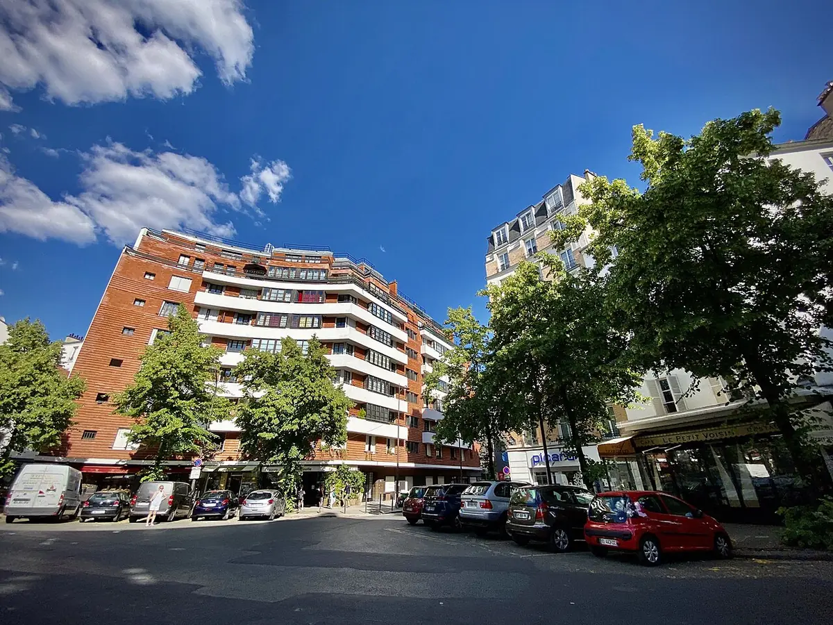Immeuble en brique orangée le long d’une rue ensoleillée à Javel