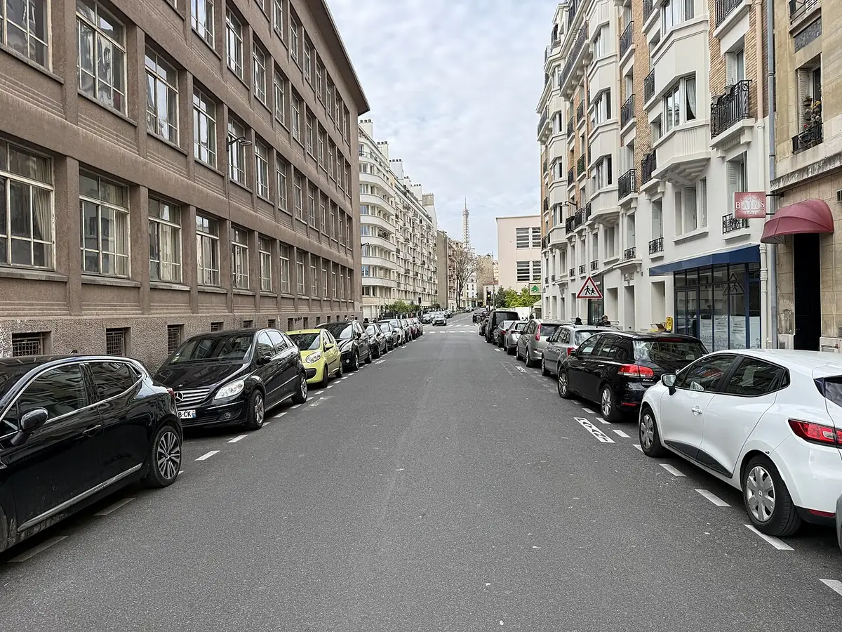 Une rue calme bordée de voitures garées et d’immeubles