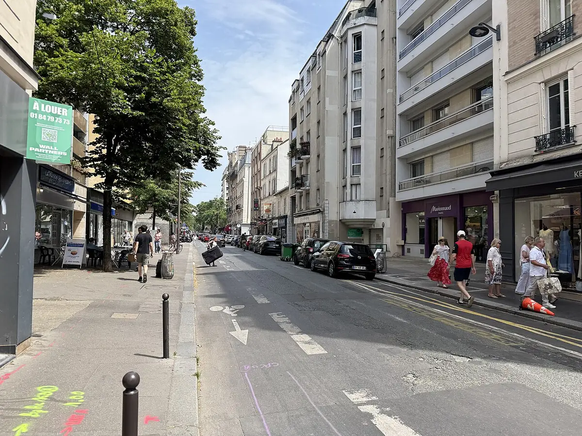 Une rue commerçante colorée avec piste cyclable et passants