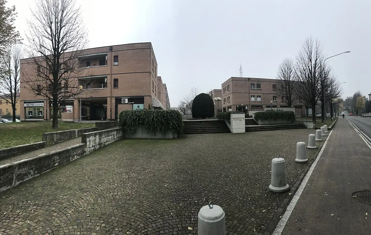 Immeubles beiges et allée pavée du quartier Betulla 21 à Reggio d’Émilie, arbres dénudés