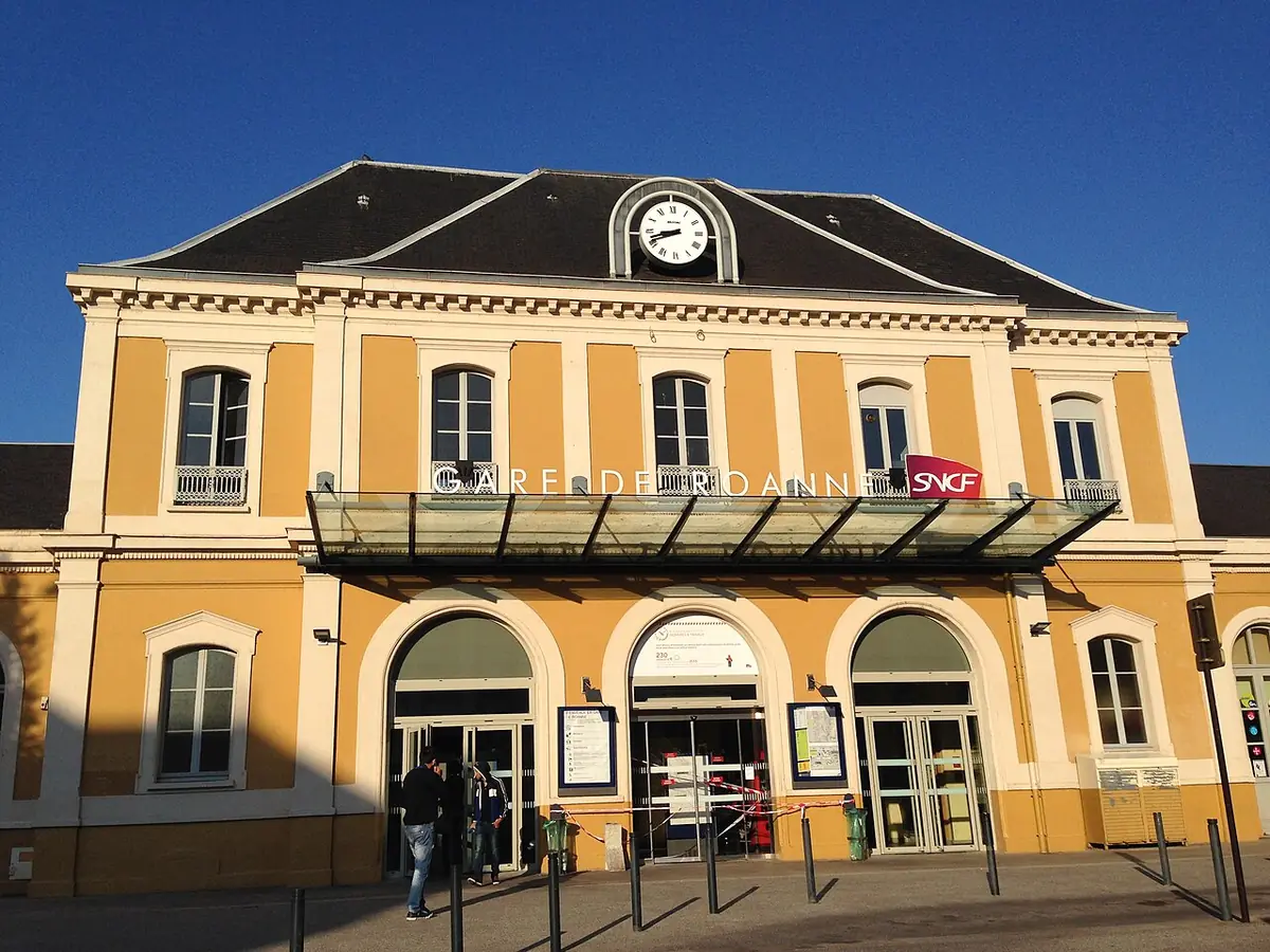 Façade jaune de la gare de Roanne avec son horloge sous un ciel bleu
