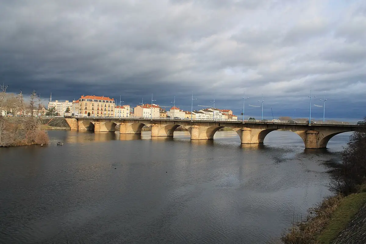 Le pont du Coteau sur la Loire à Roanne, maisons alignées sur la rive sous un ciel chargé