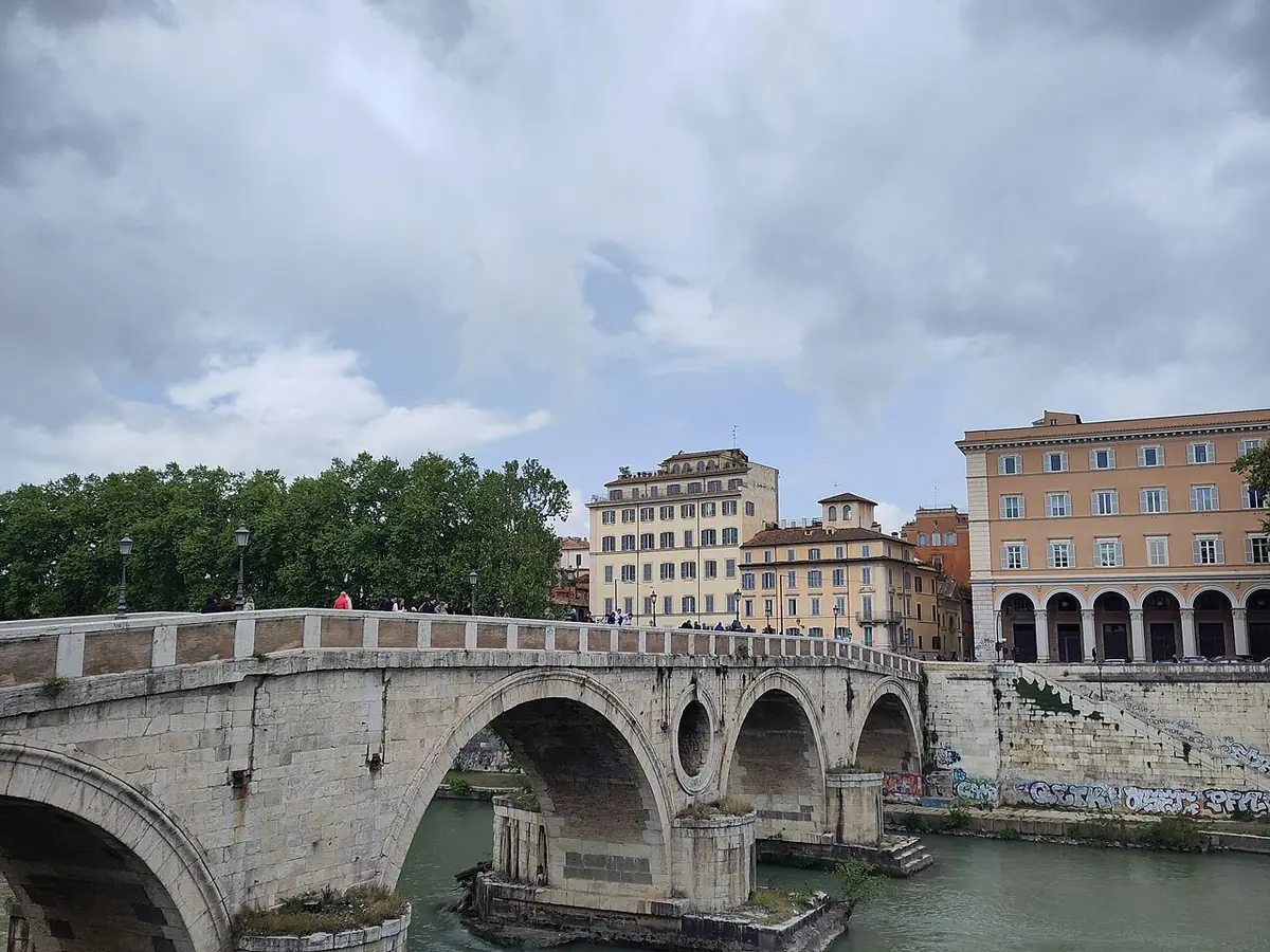 Pont de pierre à arches sur le Tibre à Rome, immeubles ocre sur la rive