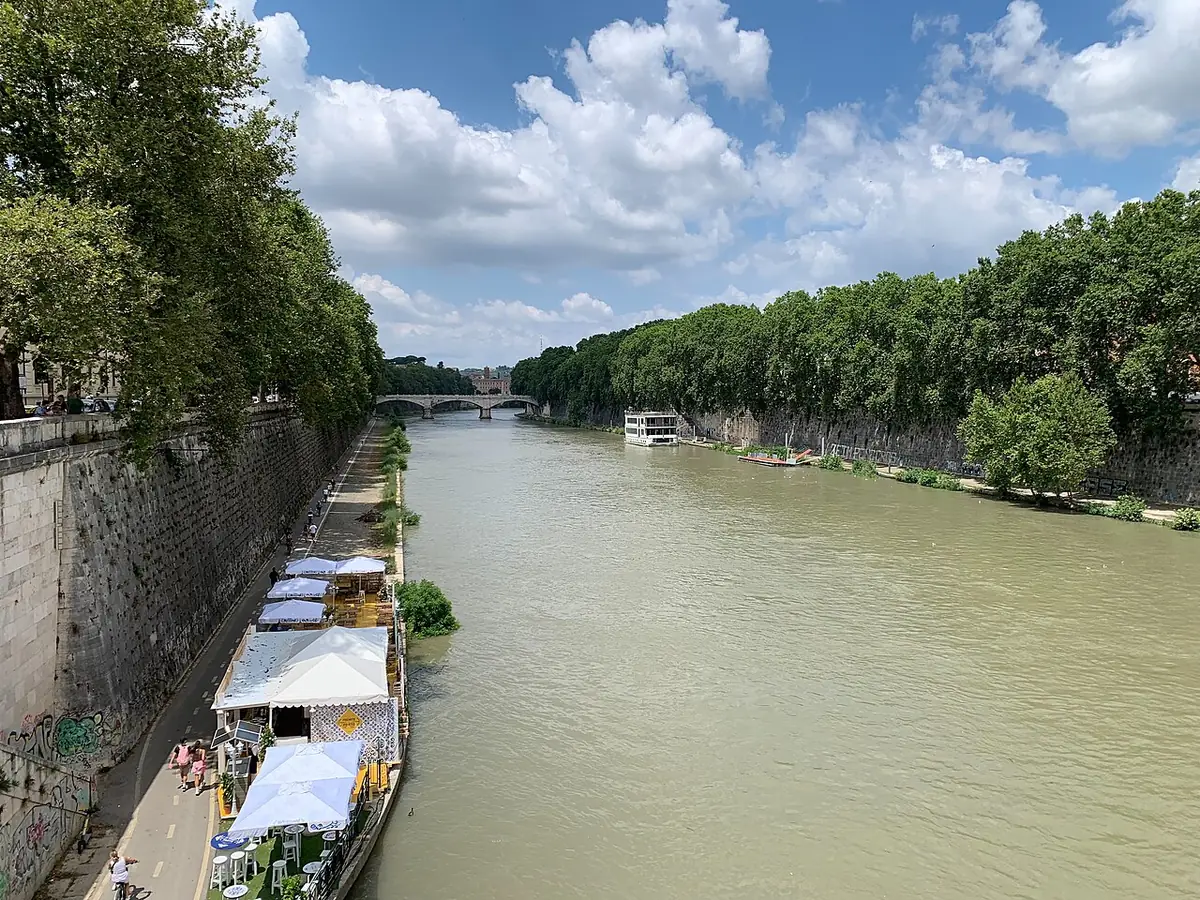 Le Tibre à Rome entre ses hauts quais arborés, péniches amarrées sur la rive