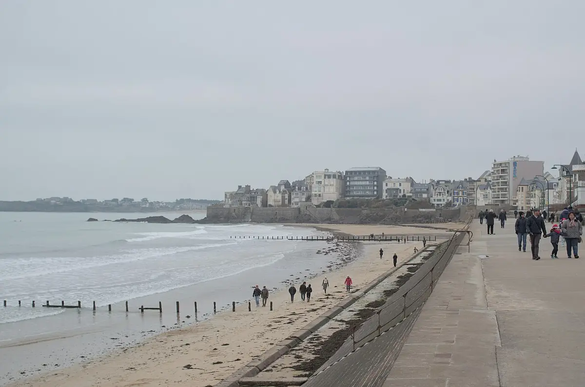 Promeneurs sur la digue de Saint-Malo en hiver, immeubles le long de la plage