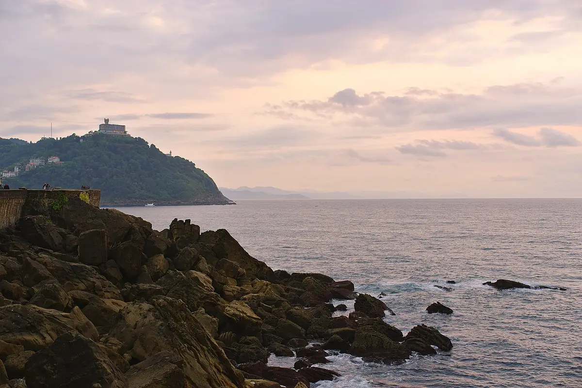 Rochers du Paseo Nuevo et mont Igueldo au-dessus de la mer, sous un ciel rosé